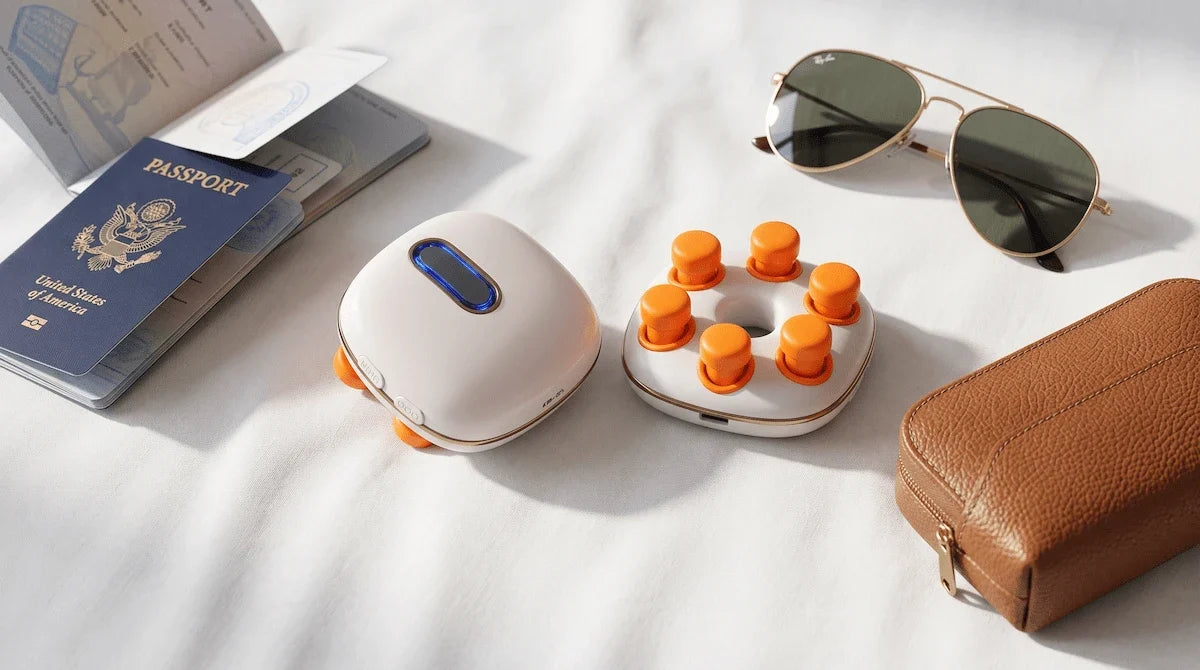 Top-down view of travel essentials including a passport and a compact portable eye massager.