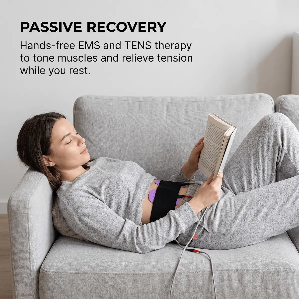 Woman using hands-free EMS electrode pads on her abdomen while resting — demonstrating passive muscle stimulation with the Elevaure RF Cavitation Massage System's 8-channel EMS mode.