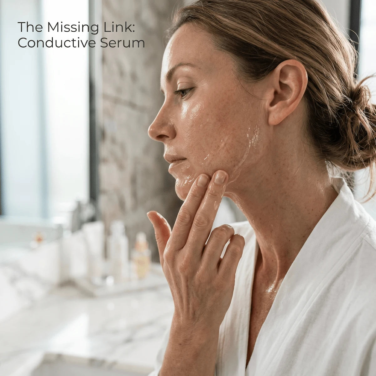 A woman applying a water-based conductive serum to her jawline, an essential step for effective EMS device use.