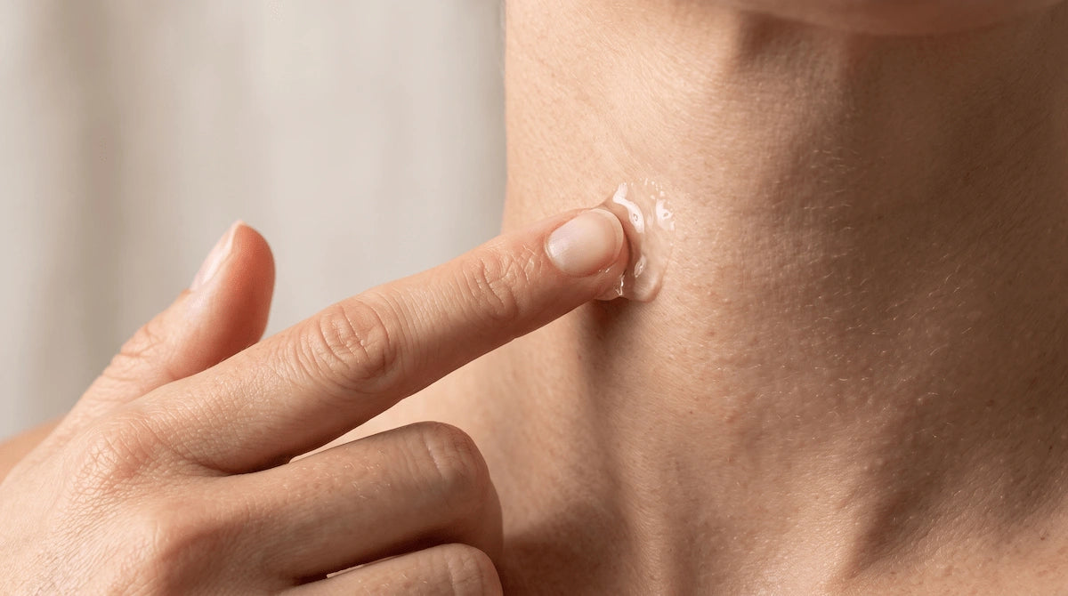 Fingers applying clear conductive gel to the neck before using an RF device.