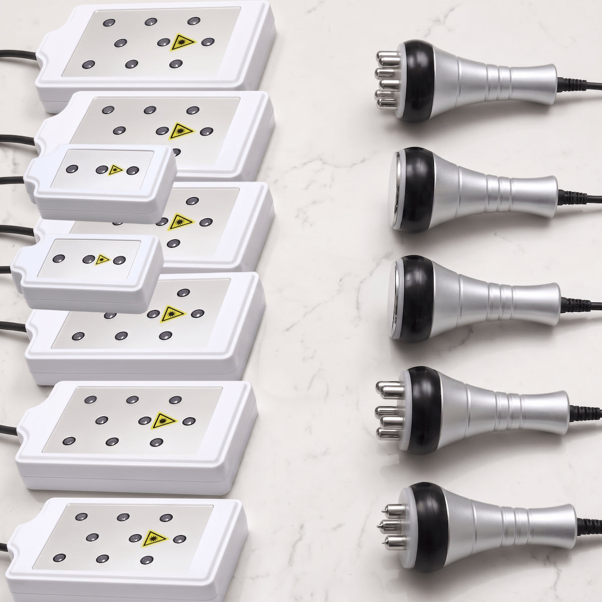 Flat lay presentation of all 6-in-1 system attachments, including 8 LLLT pads, RF probes, cavitation head, and vacuum handle.