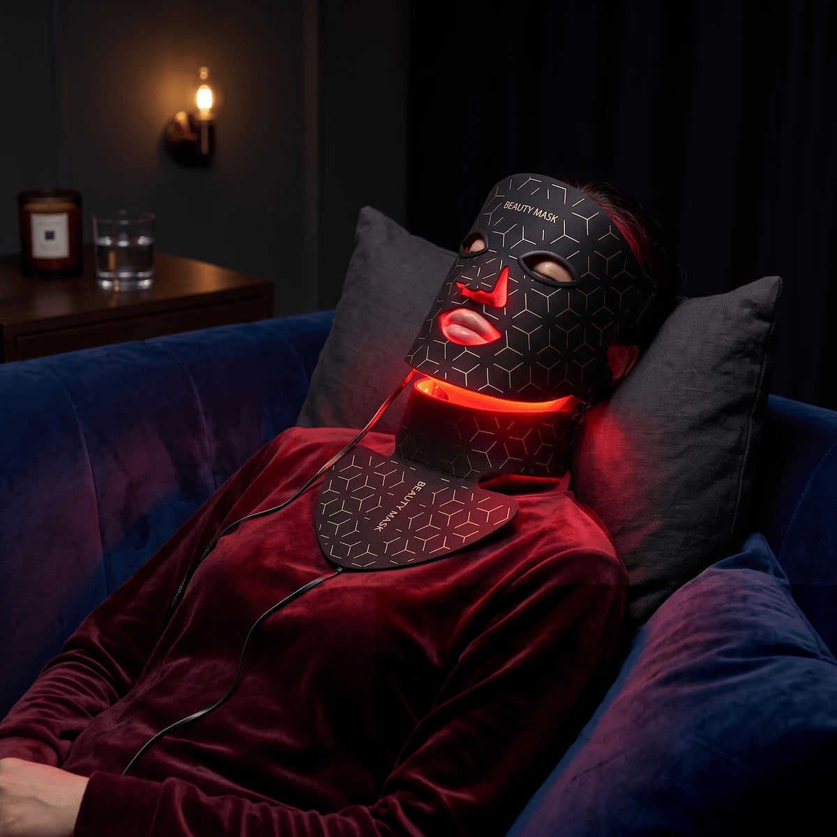 Woman relaxing in the evening while wearing an Elevaure red LED light therapy mask for daily anti-aging repair.