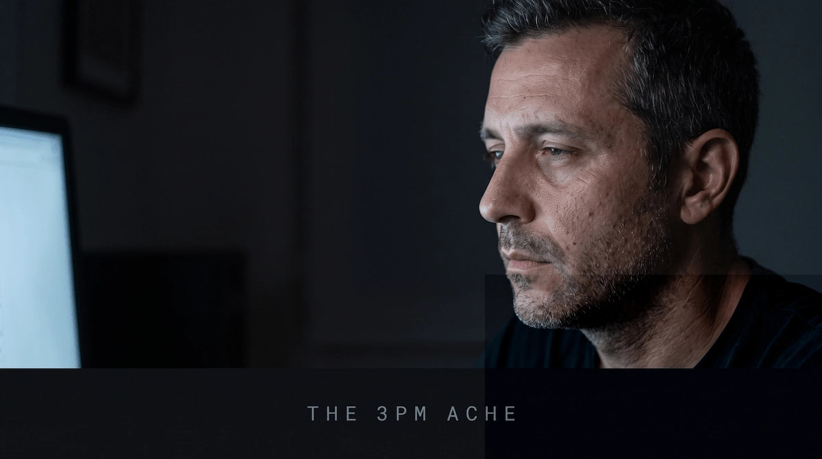 Close up of a man looking stressed while staring at a computer screen in the dark.
