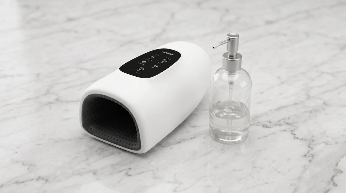 Elevaure hand massager styled with a glass dispenser on white marble.