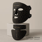 The Elevaure clinical-grade LED light therapy mask and neck attachment resting on a minimalist marble surface.