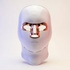 White minimalist LED light therapy mask for face and neck by Elevaure, featuring rose gold accents, intuitive touch sensor, and functional ventilation grid.