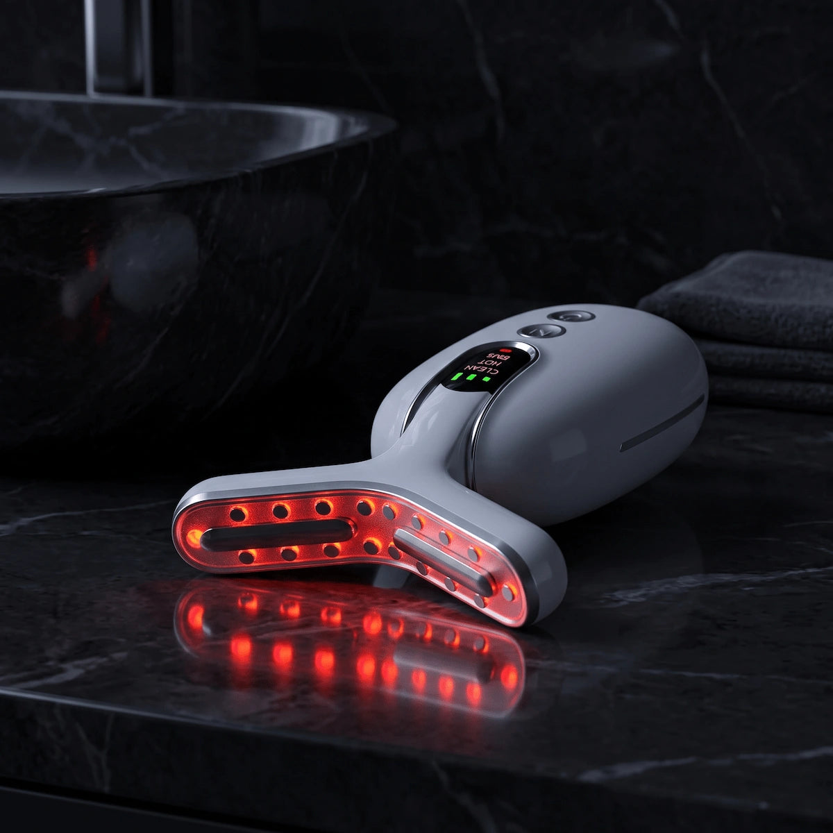 Elevaure neck tightening device emitting red LED light on a dark marble vanity.