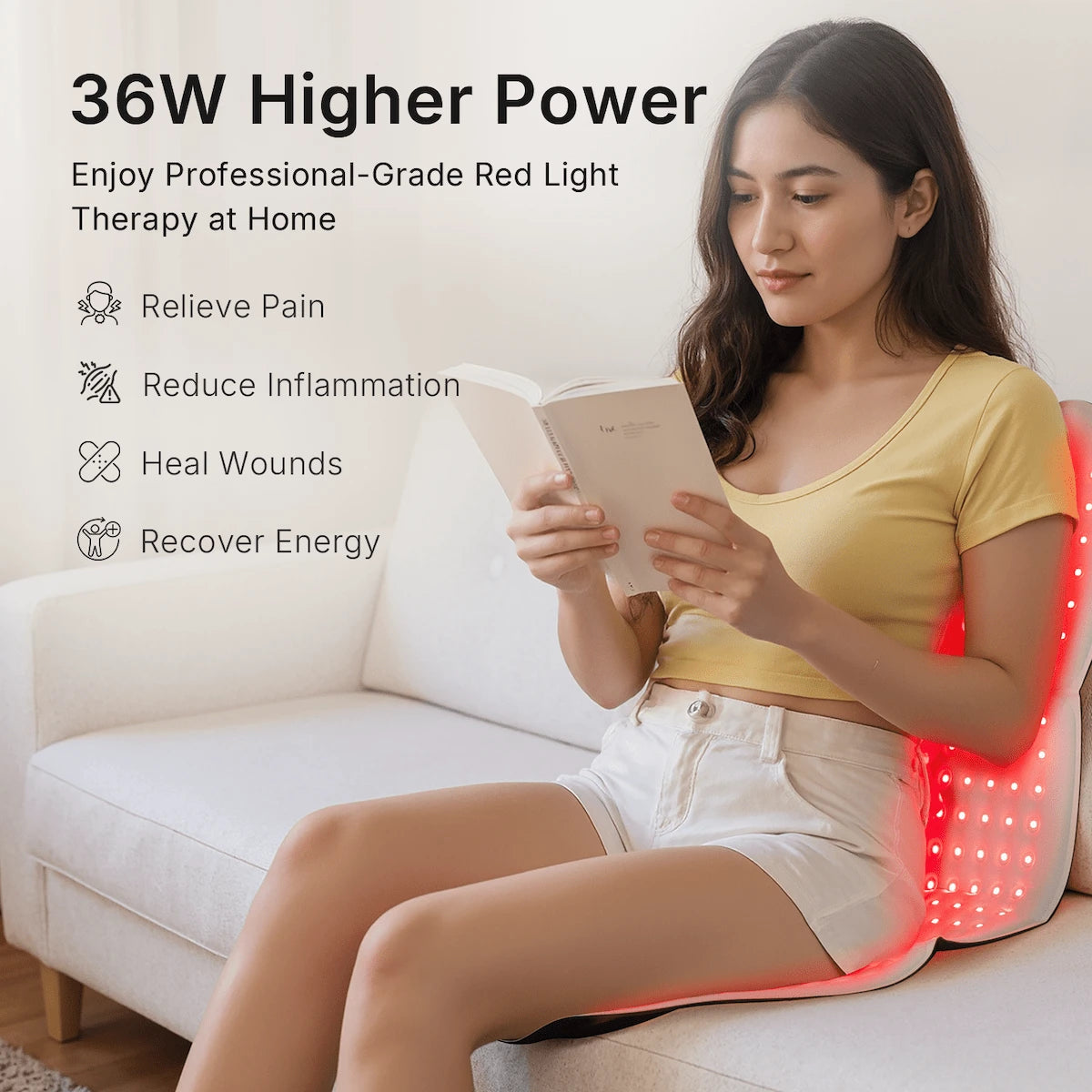 Woman relaxing on a couch reading while using the 36W large red light therapy pad draped behind her back for at-home lumbar relaxation.