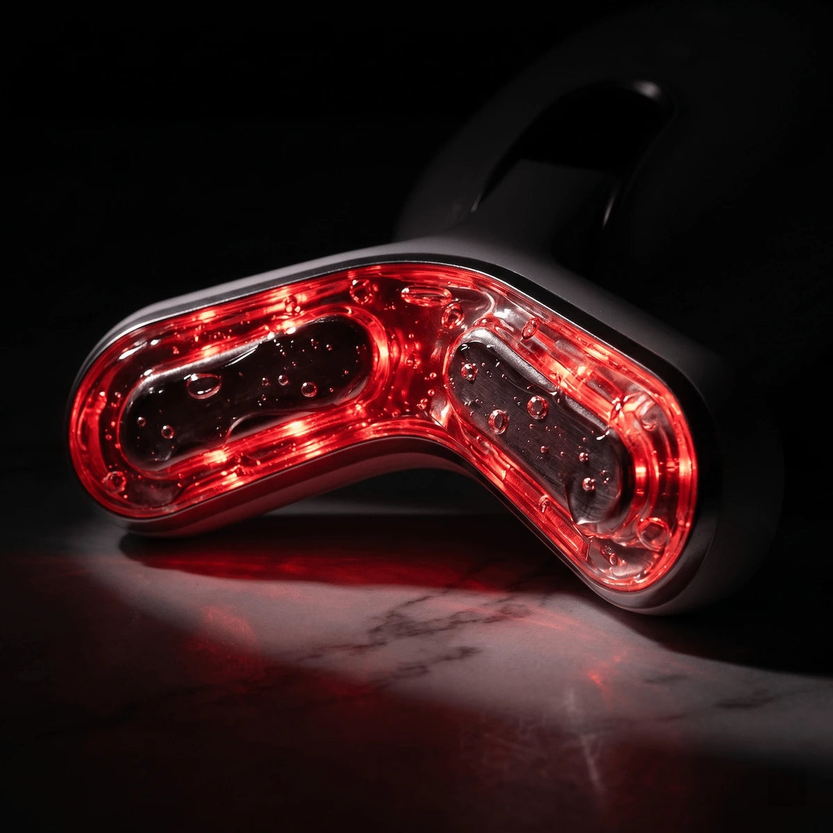 Macro close-up of the ELEVAURE RF device massage head emitting red light therapy for deep collagen stimulation and skin tightening.