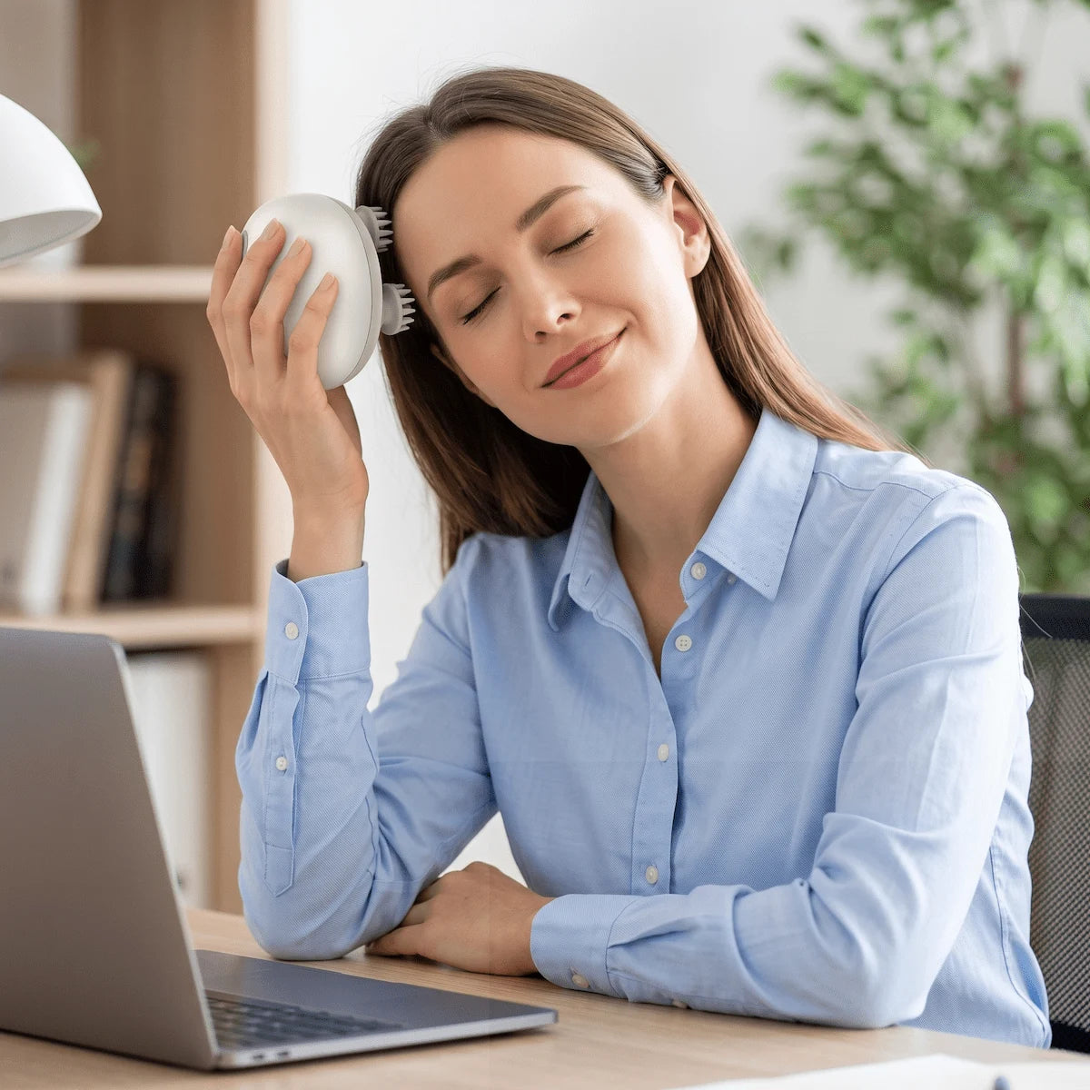Professional using a cordless scalp massager at their desk to relieve stress and reduce scalp tension.