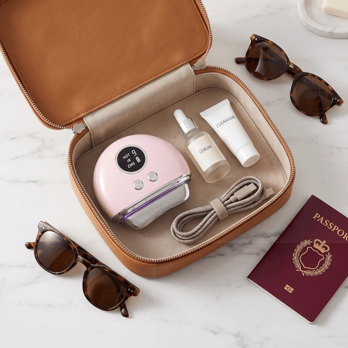 Travel flat lay featuring a compact 4-in-1 EMS face massager and essential skincare products.